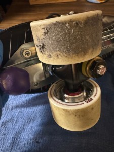 An off-white rollerskate wheel with a bunch of rink crud on it, making it fuzzy and grey